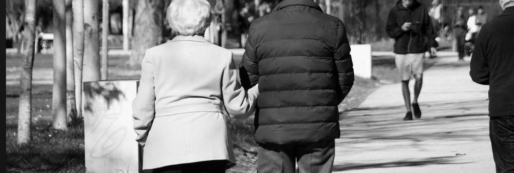 Two people walking together down a tree-lined path